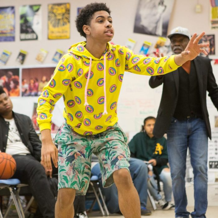 A high school drama student rehearses a scene while his instructor looks on.