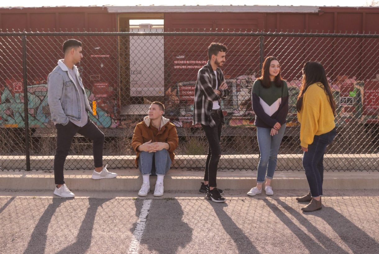 A group of teenagers standing on a basketball field talking amongst themselves